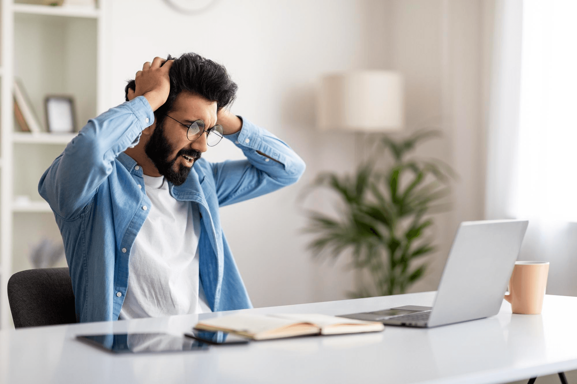 A man looking stressed at his workplace because he lost his job and is worried about his financial security.